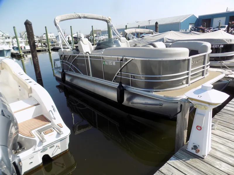 Slide: The Image of 2021 Sylvan Mirage 8522 LZ pontoon boat docked at a marina. - 2