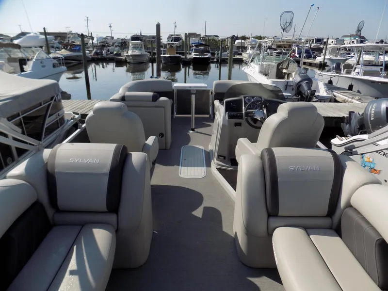 Slide: The Image of 2021 Sylvan Mirage 8522 LZ pontoon boat interior at marina, showcasing seating and helm. - 5