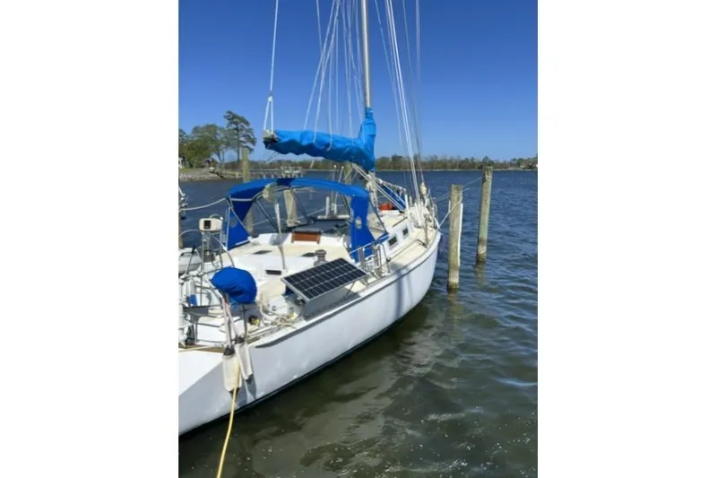 Slide: The Image of 1984 Morgan 454 sailboat docked on calm water with blue sails and solar panels. - 39
