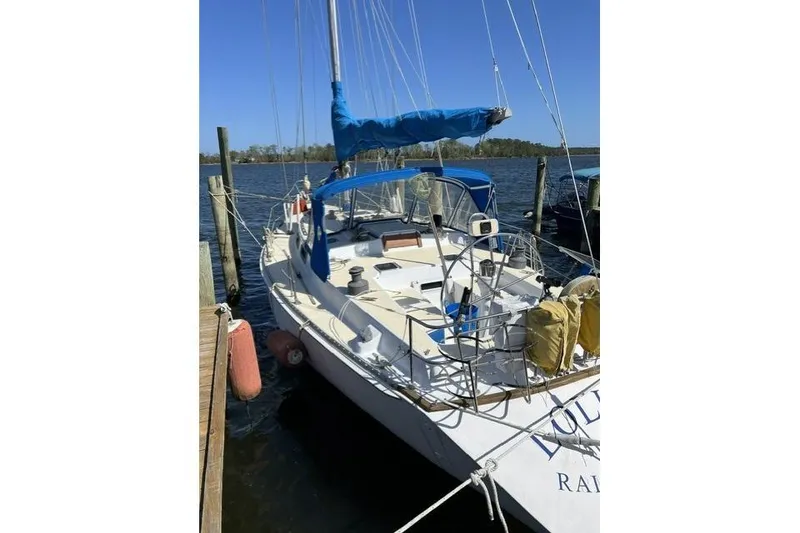 Slide: The Image of 1984 Morgan 454 sailboat docked, featuring blue sail cover and spacious deck. - 40