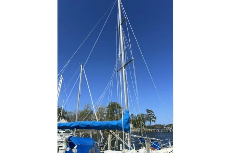 Slide: The Image of 1984 Morgan 454 sailboat with blue sails docked under clear sky. - 43