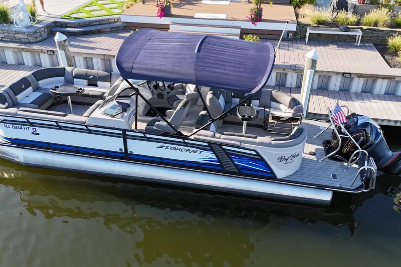 Slide: The Image of 2023 Starcraft MX 25 R DC pontoon boat docked with canopy and seating. - 2