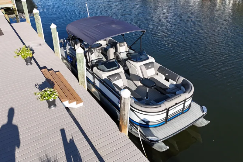 Slide: The Image of 2023 Starcraft MX 25 R DC pontoon boat docked on calm water. - 4