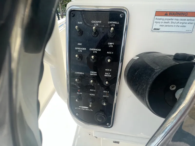 Slide: The Image of Control panel of a 2020 Cobia 220 boat with various switches and warning label. - 10