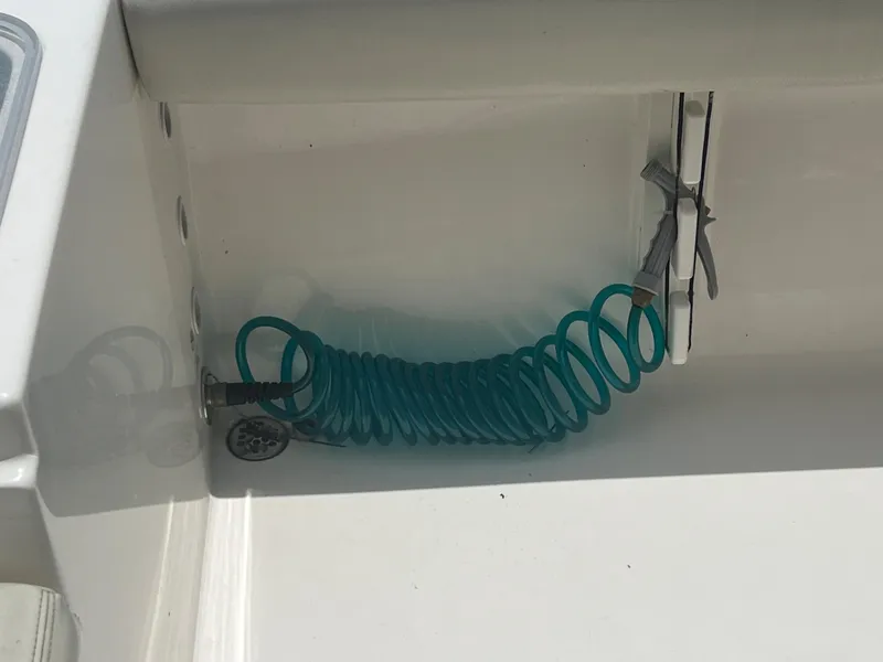 Slide: The Image of Coiled blue hose in a 2020 Cobia 220 boat's storage compartment. - 17
