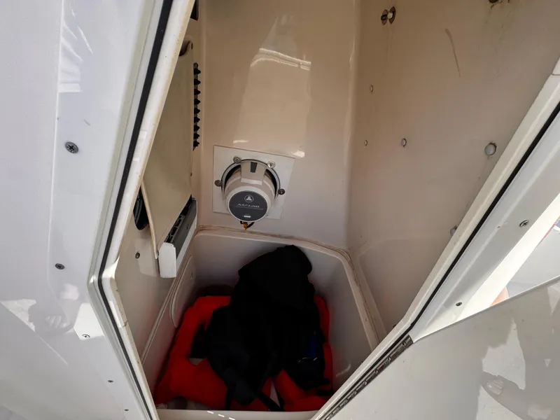 Slide: The Image of Storage compartment inside 2020 Cobia 220 boat, featuring a switch and life jackets. - 29
