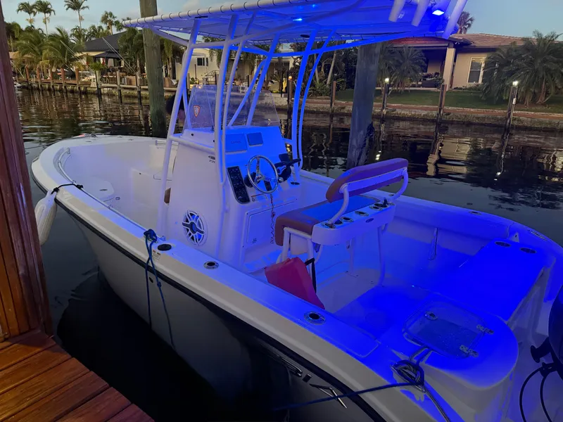 Slide: The Image of 2020 Cobia 220 boat docked, illuminated by blue lights, with a center console and seating. - 41