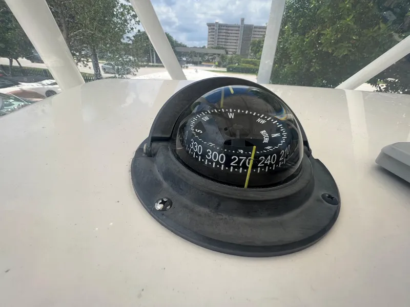 Slide: The Image of Compass on 2020 Cobia 220 boat, outdoor setting with trees and buildings in background. - 9