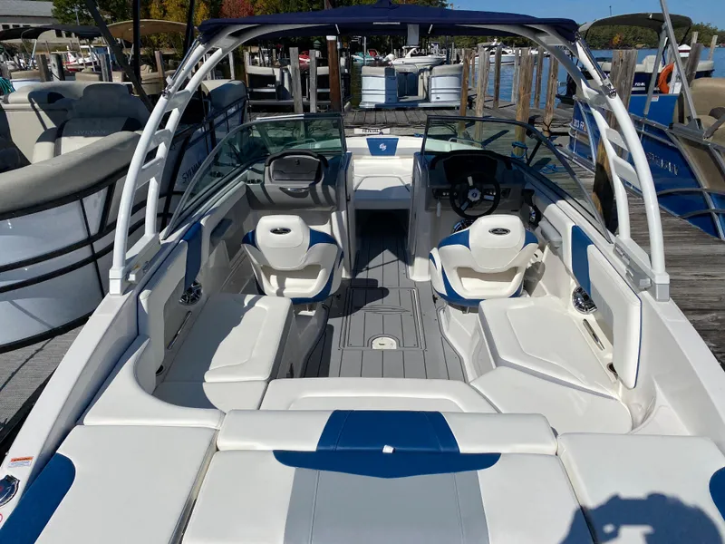 Slide: The Image of 2022 Chaparral 23 SSi boat interior with white and blue seating at a dock. - 11