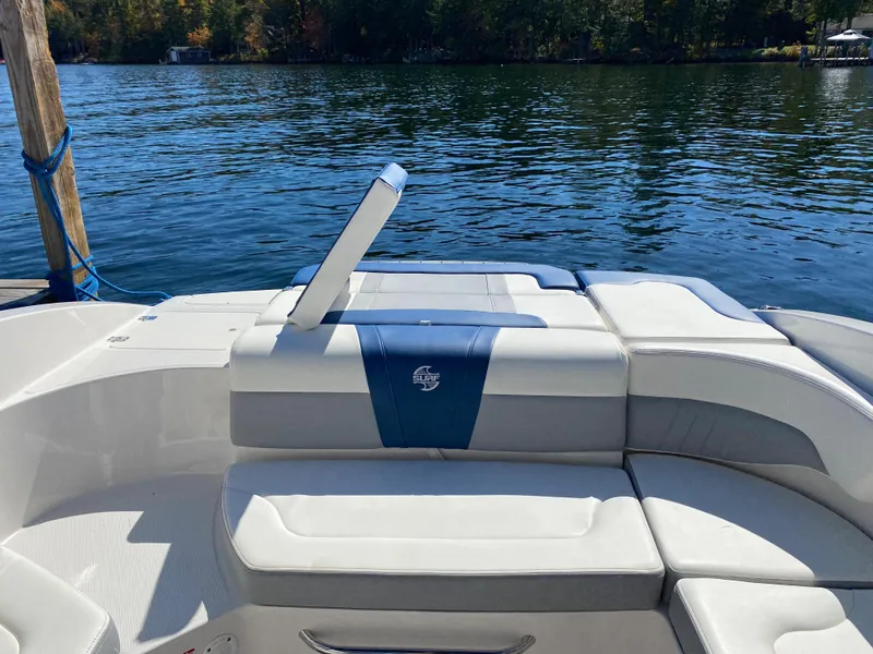 Slide: The Image of 2022 Chaparral 23 SSi boat interior with white and blue seating on a lake. - 16