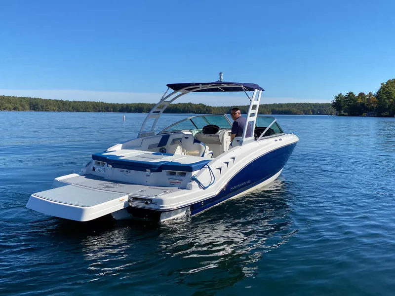 Slide: The Image of 2022 Chaparral 23 SSi boat on a serene lake with a clear blue sky. - 19