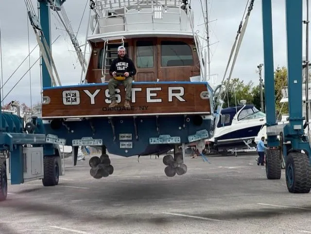 Slide: The Image of Custom Carolina Ritchie Howell 60 Sportfish 2012 boat in dry dock with person sitting on stern. - 23