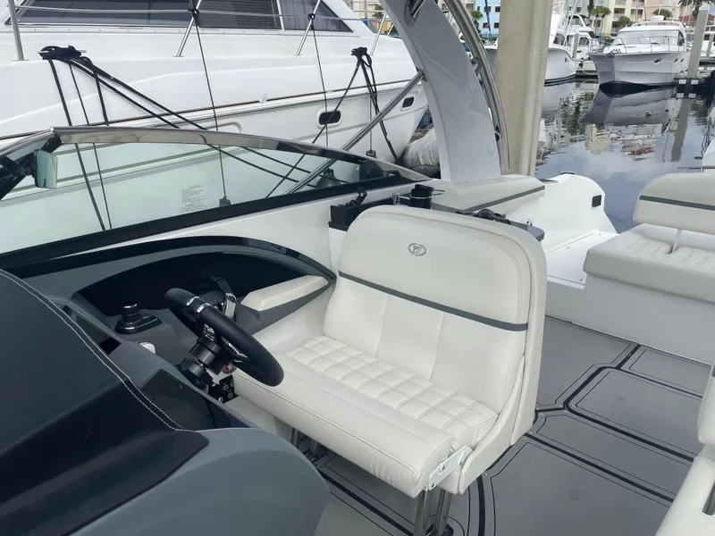 Slide: The Image of 2022 Cobalt 30SC boat interior with white seating and steering wheel at marina. - 21