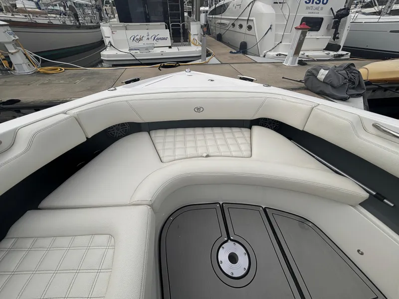Slide: The Image of 2022 Cobalt 30SC boat interior with white cushioned seating at a marina. - 33