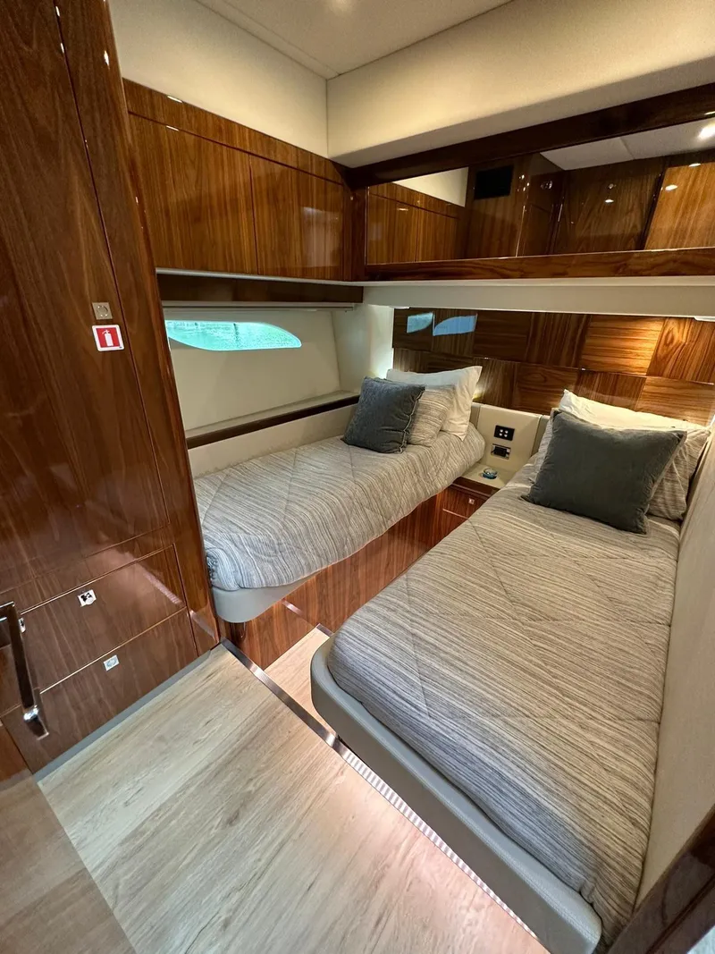 Slide: The Image of Luxurious 2018 Riviera 60SY yacht cabin with twin beds and elegant wood finish. - 12