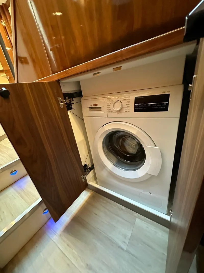 Slide: The Image of Built-in washing machine in 2018 Riviera 60SY yacht, wooden cabinetry, modern interior design. - 19
