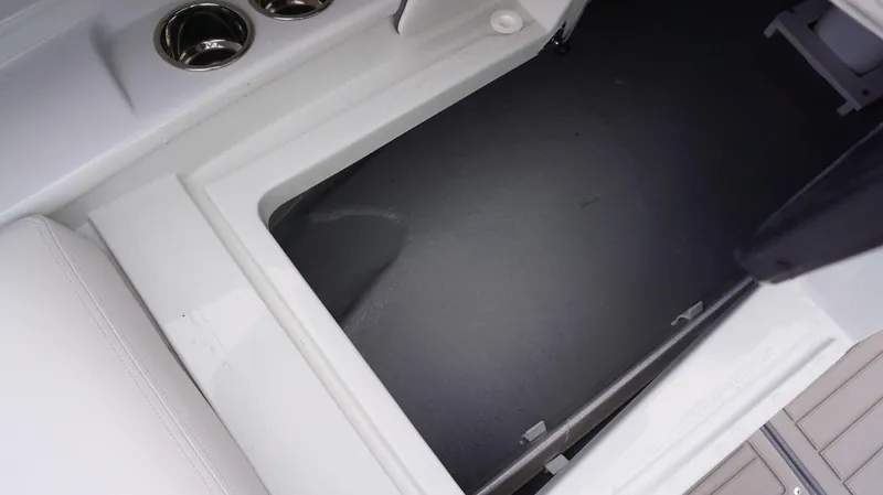 Slide: The Image of Storage compartment of 2024 Crownline 260 XS boat with cup holders and white seating. - 10