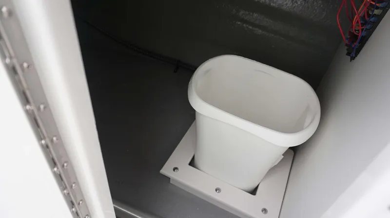 Slide: The Image of 2024 Crownline 260 XS boat interior storage compartment with white trash bin. - 17