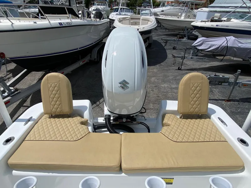 Slide: The Image of 2023 Savannah SS21 boat with beige seating and outboard motor in a marina. - 23