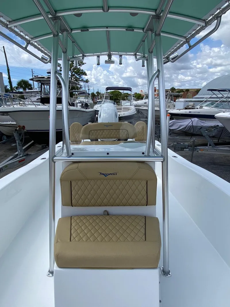Slide: The Image of 2023 Savannah SS21 boat with tan seats and green canopy in a marina. - 9