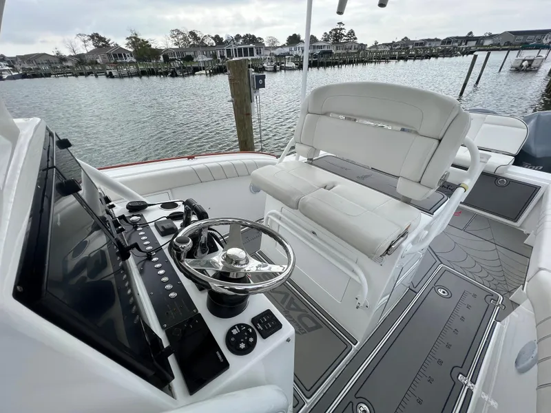 Slide: The Image of 2018 Buddy Davis 34 boat cockpit with steering wheel and seating, docked by waterfront homes. - 21