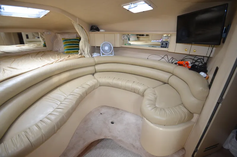 Slide: The Image of 1998 Sea Ray 310 cabin interior with beige leather seating and TV. - 12