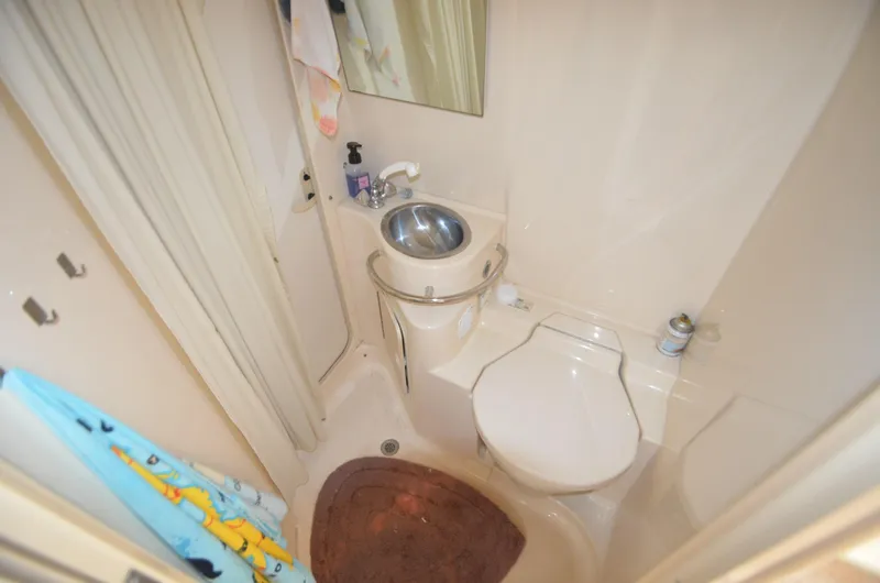 Slide: The Image of Compact bathroom in a 1998 Sea Ray 310 boat with sink, toilet, and shower. - 13