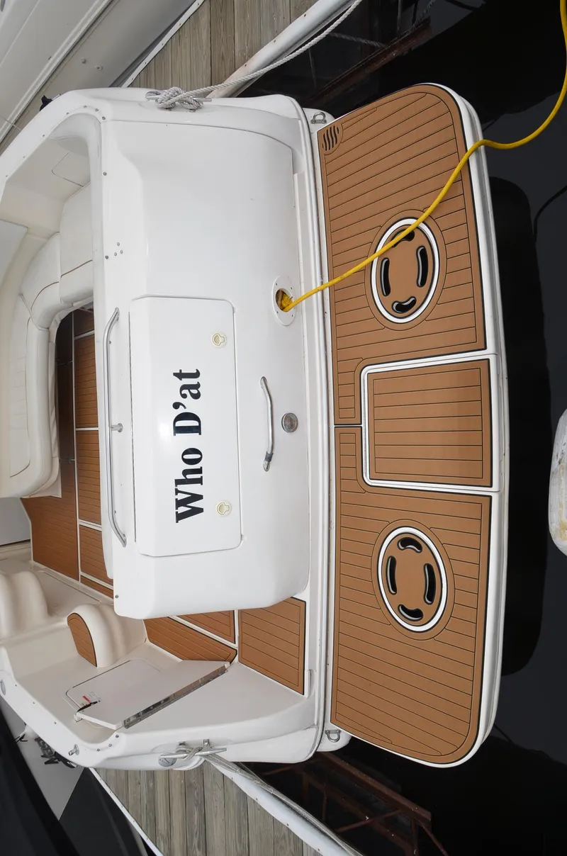 Slide: The Image of 1998 Sea Ray 310 boat docked, named Who D'at, with teak deck and white seating. - 8