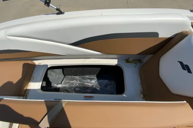 Slide: The Image of 2024 Starcraft SVX 191 boat storage compartment with tan and white seating. - 13