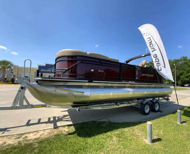 Slide: The Image of 2024 Starcraft SLS 3 pontoon boat on trailer, displayed outdoors. - 2