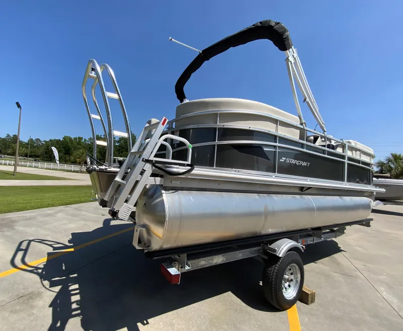 Slide: The Image of 2024 Starcraft LX20 R pontoon boat on a trailer in a parking lot. - 2