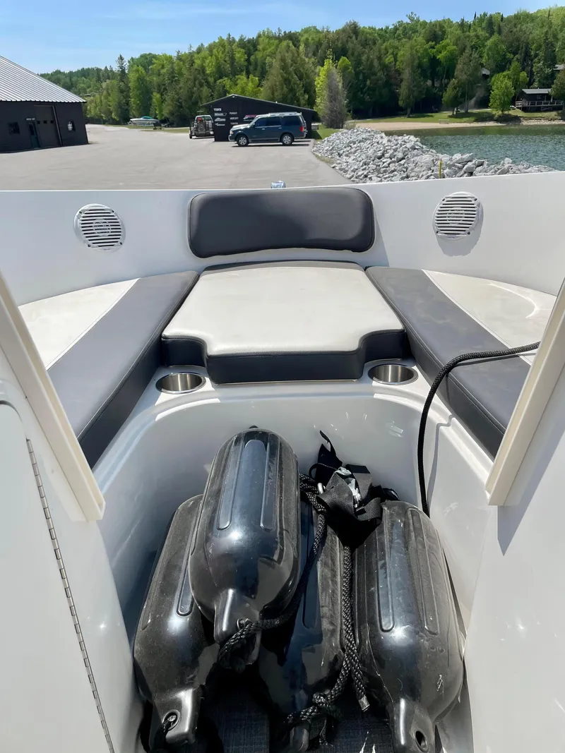 Slide: The Image of 2021 Bayliner VR5 boat interior with seating and fenders, docked near a scenic lake. - 18