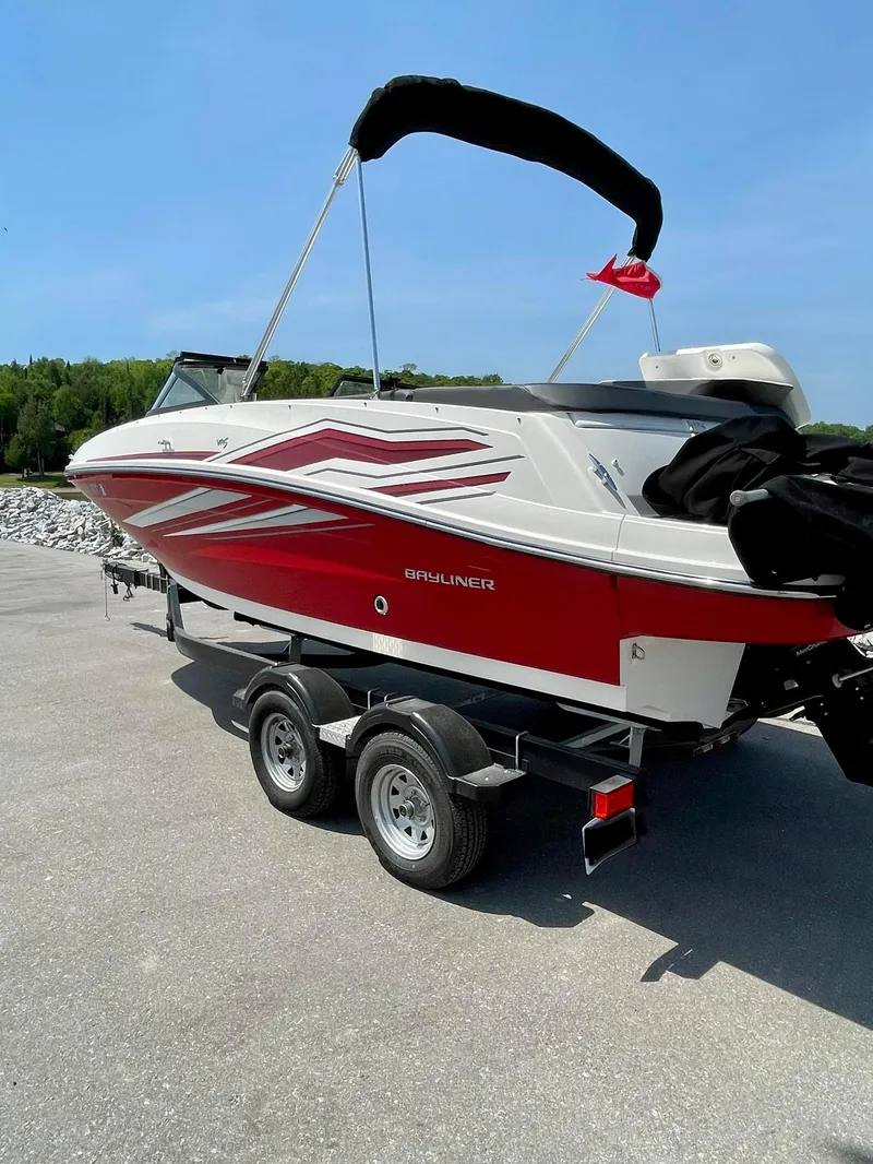 Slide: The Image of 2021 Bayliner VR5 boat on trailer, red and white design, parked outdoors. - 2