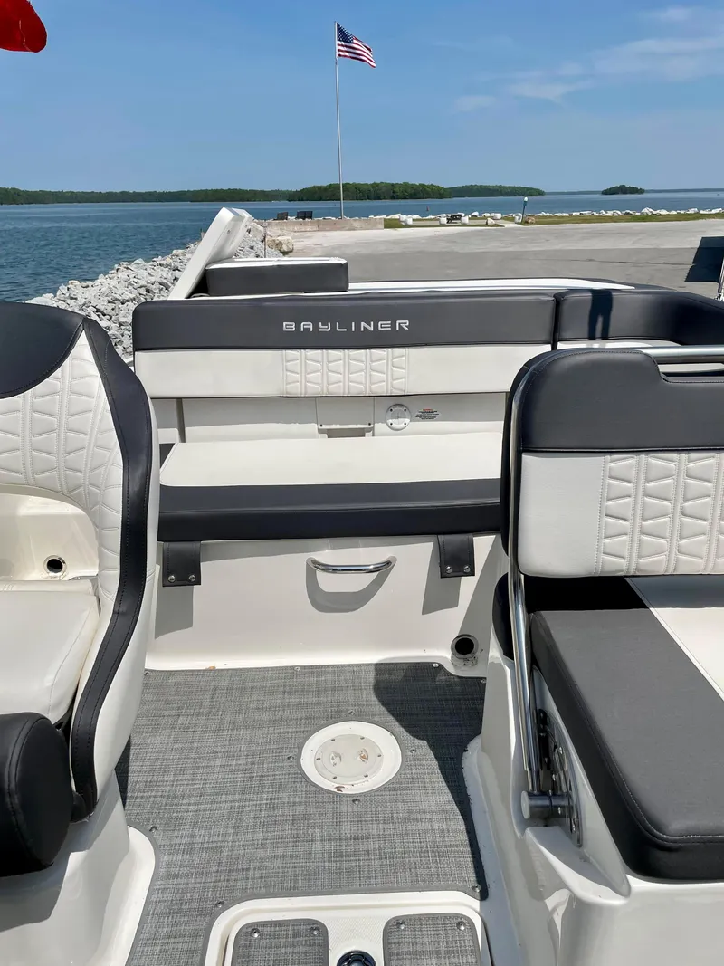 Slide: The Image of 2021 Bayliner VR5 boat interior with seating, docked by a lake with an American flag. - 24