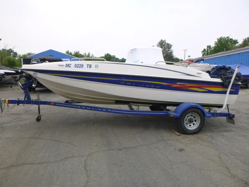 Slide: The Image of 2007 Bayliner 197 Deck Boat on a blue trailer in a parking lot. - 4