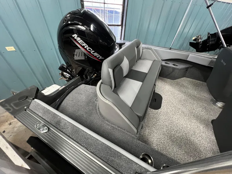 Slide: The Image of 2023 MirroCraft 176 Dual Impact boat interior with Mercury engine, gray seating, and carpeted flooring. - 4