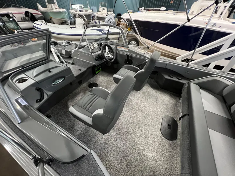 Slide: The Image of 2023 MirroCraft 176 Dual Impact boat interior with gray seating and modern dashboard. - 6