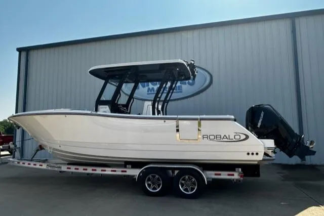Slide: The Image of 2023 Robalo R270 boat on trailer outside a marine dealership. - 1