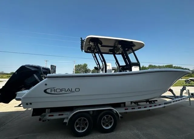 Slide: The Image of 2023 Robalo R270 boat on a trailer under clear blue sky. - 2