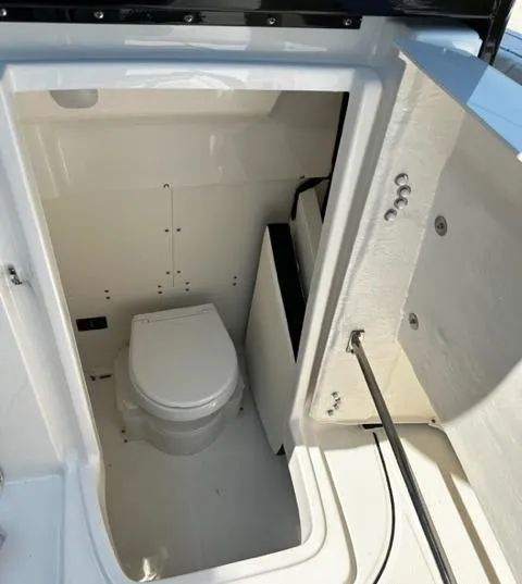 Slide: The Image of 2023 Robalo R270 boat interior with a compact marine toilet. - 6