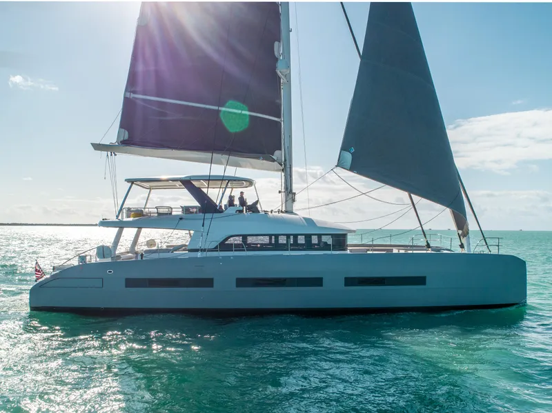 Slide: The Image of 2020 Lagoon SEVENTY 7 sailing catamaran on open water, sunlit and elegant. - 13