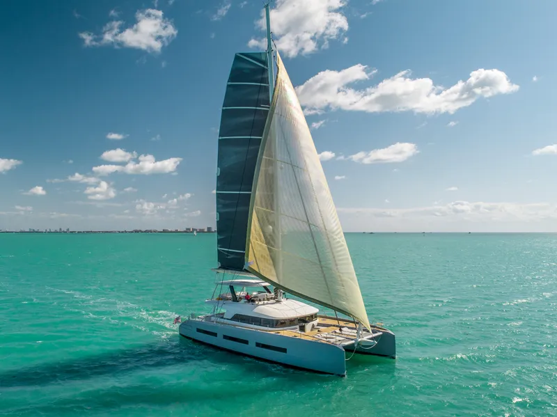 Slide: The Image of 2020 Lagoon SEVENTY 7 catamaran sailing on turquoise waters under a clear blue sky. - 25