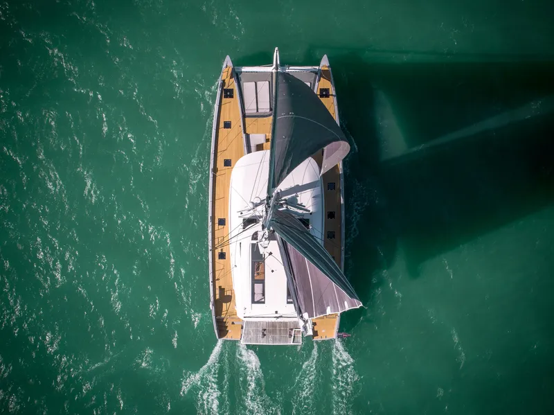 Slide: The Image of Aerial view of 2020 Lagoon SEVENTY 7 catamaran sailing on turquoise water. - 31