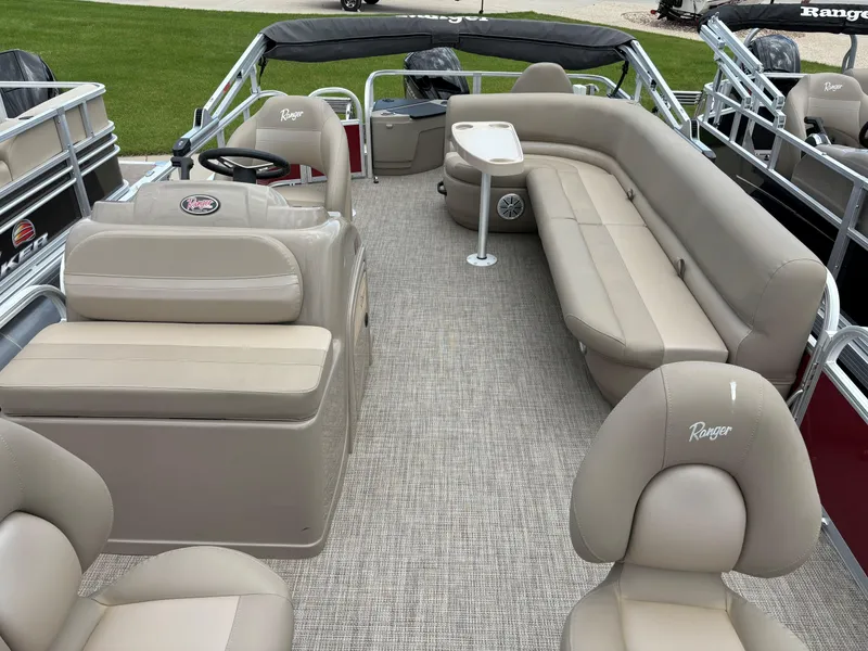 Slide: The Image of 2023 Ranger Reata 200F pontoon boat interior with beige seating and steering console. - 5