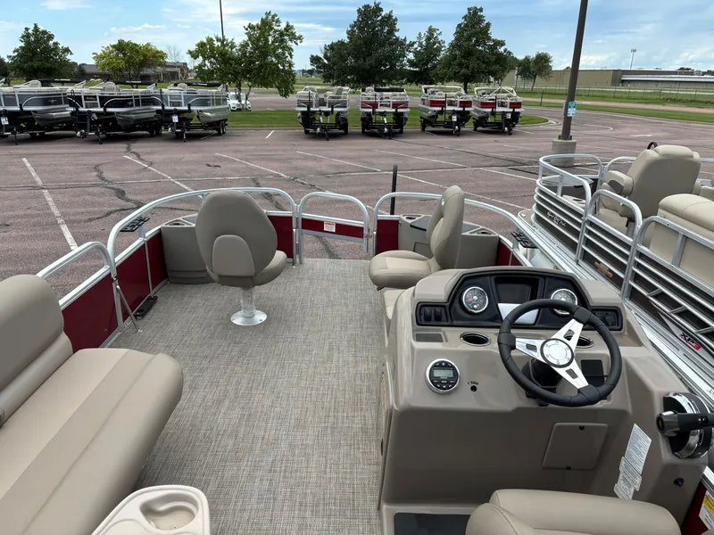 Slide: The Image of 2023 Ranger Reata 200F pontoon boat interior with beige seating and steering console. - 6