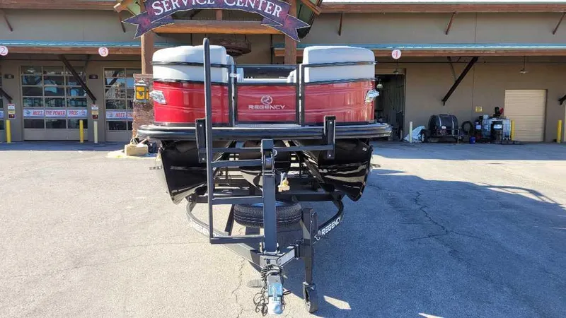 Slide: The Image of 2023 Regency 250 DL3 pontoon boat at service center, front view. - 2
