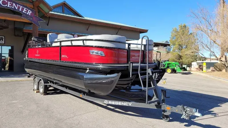 Slide: The Image of 2023 Regency 250 DL3 pontoon boat on trailer, red and black design, parked outdoors. - 3