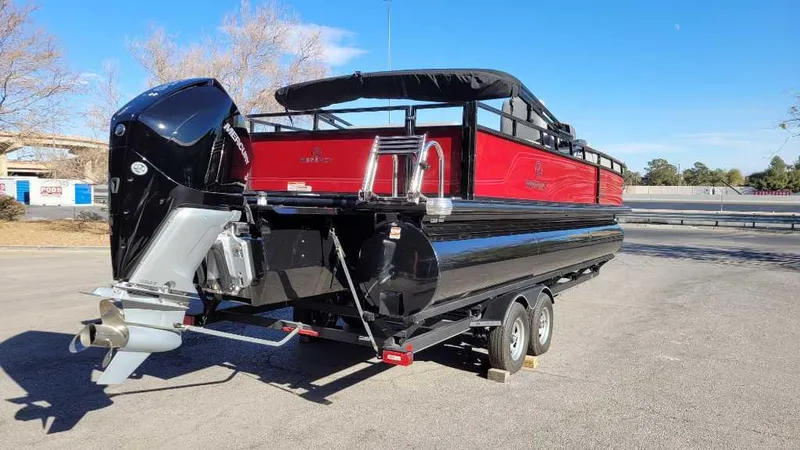 Slide: The Image of 2023 Regency 250 DL3 pontoon boat on trailer, red and black design, parked outdoors. - 4