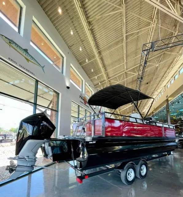 Slide: The Image of 2023 Regency 250 DL3 pontoon boat displayed indoors with a black and red exterior. - 6