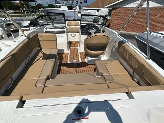 Slide: The Image of 2024 Bayliner VR4 boat interior with tan seating and wood flooring. - 10